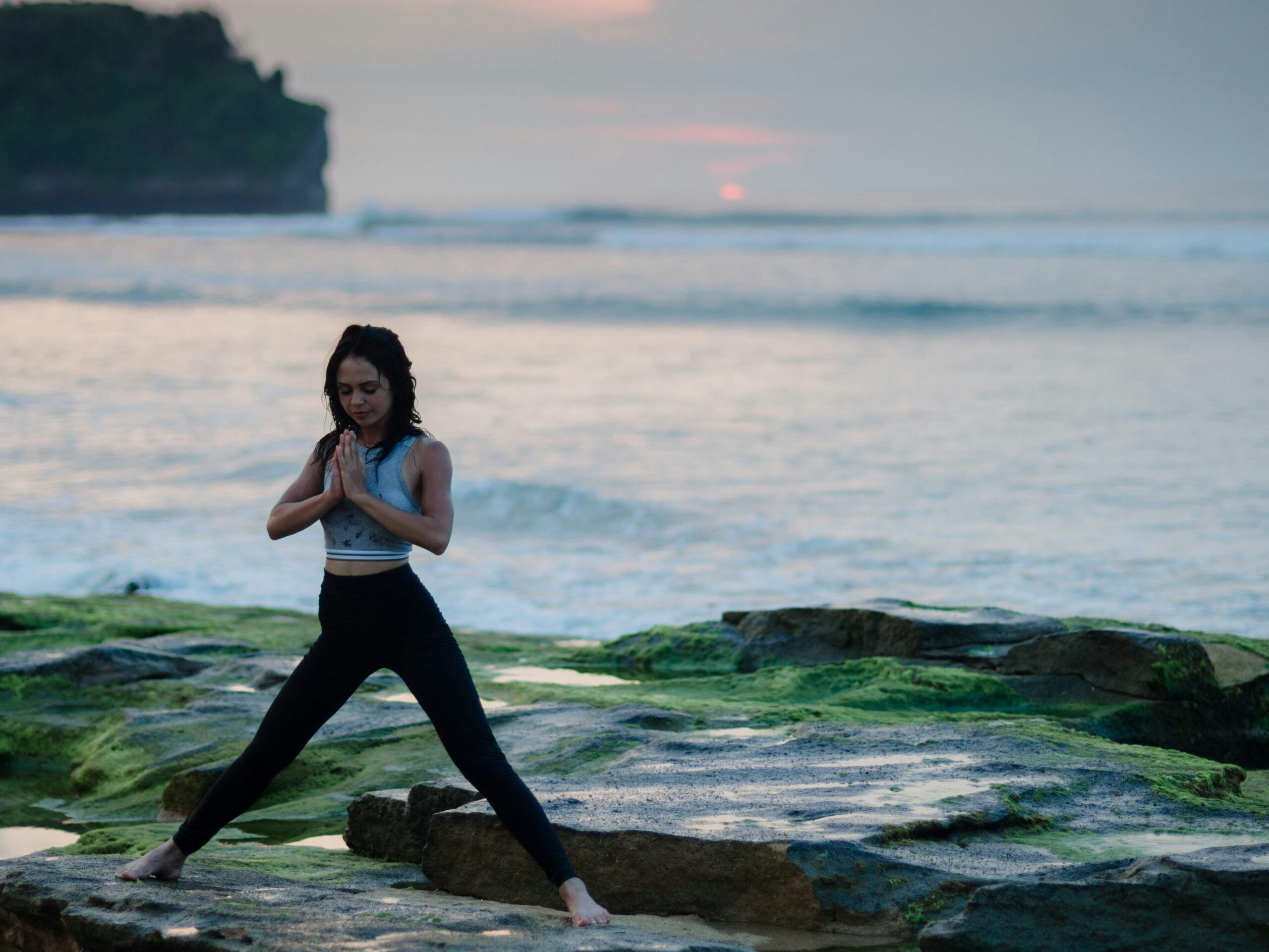 a woman standing on a rock by the water - women's health